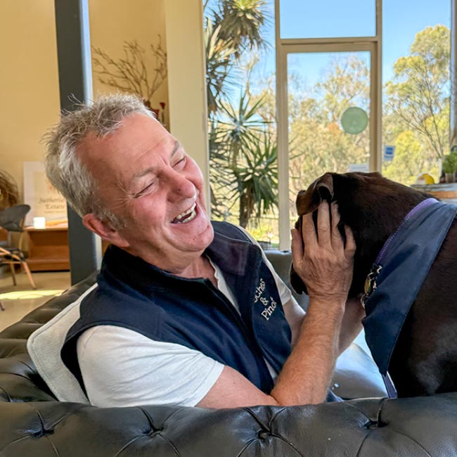 Doggy Wine Tour Guide – Jeff A man, Jeff, your tour guide, with a brown dog in his lap